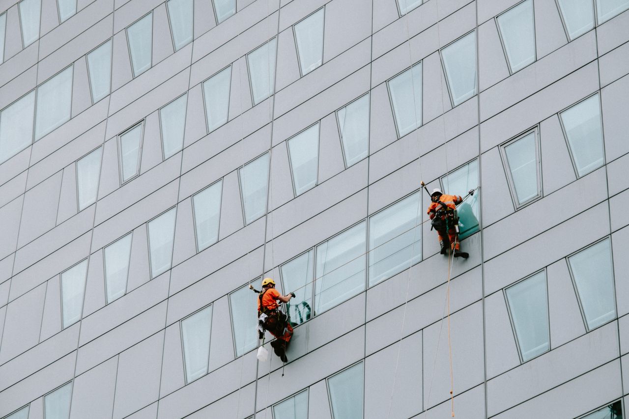 heros-img High-rise window washers in safety gear cleaning a skyscraper facade.